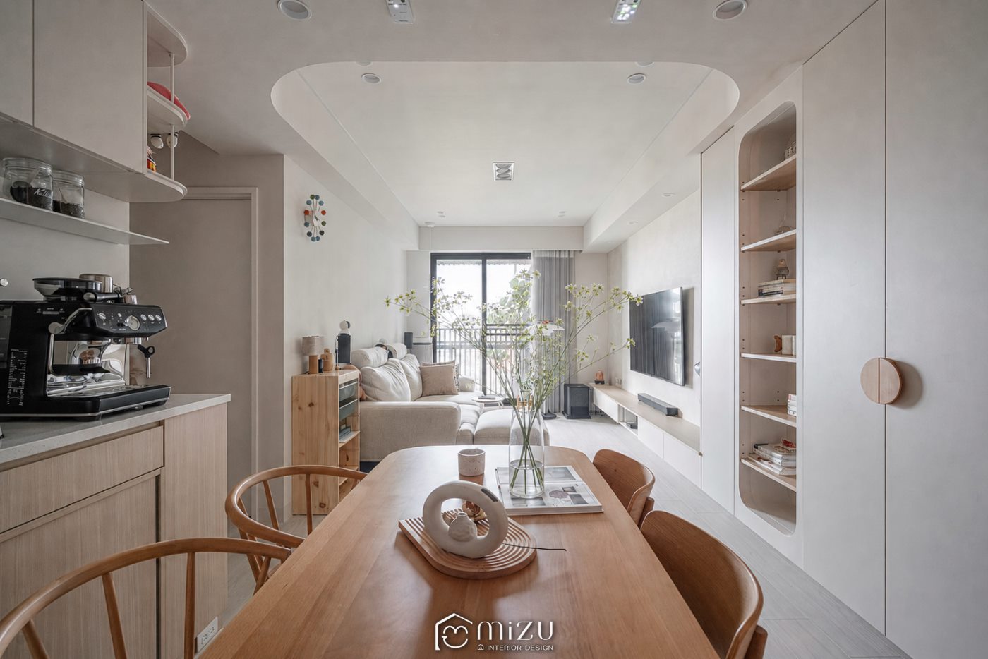 餐廳望向客廳全景，弧形天花、淺色櫃體與木質餐桌串聯開放空間 | GP7109 萊博淺橡 超耐磨木地板