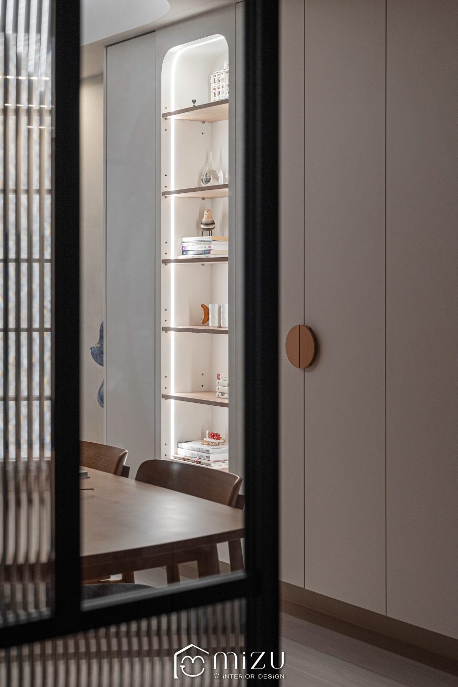 走道望向餐廳弧形玻璃展示櫃與木質餐桌